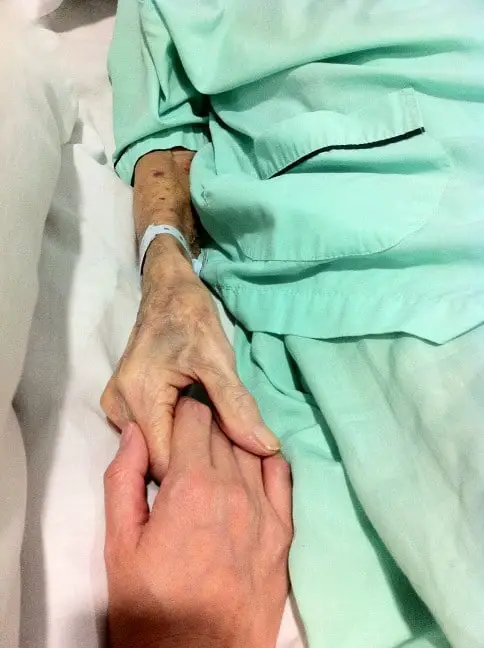 Une personne senior tenant la main de son aidant