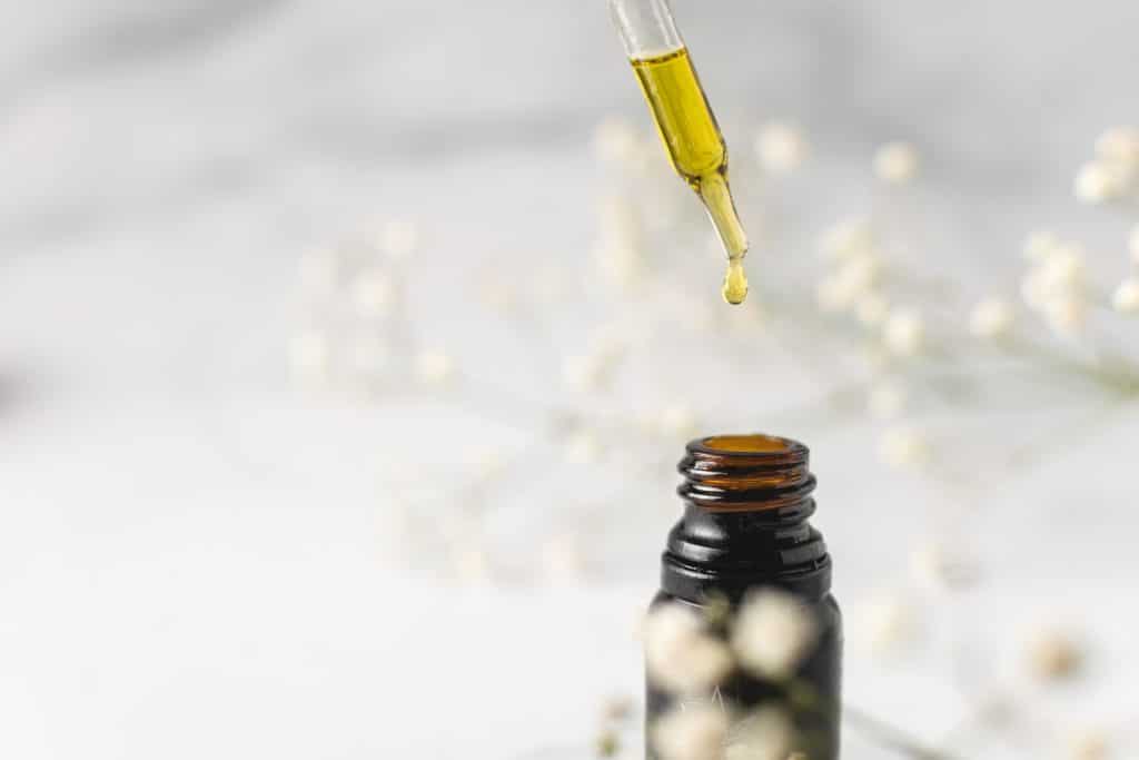 Goutte de CBD Médical qui tombe d'une pipette jusqu'à son flacon